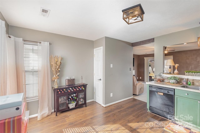 kitchen featuring ceiling fan, sink, black dishwasher, green cabinets, and dark hardwood / wood-style floors