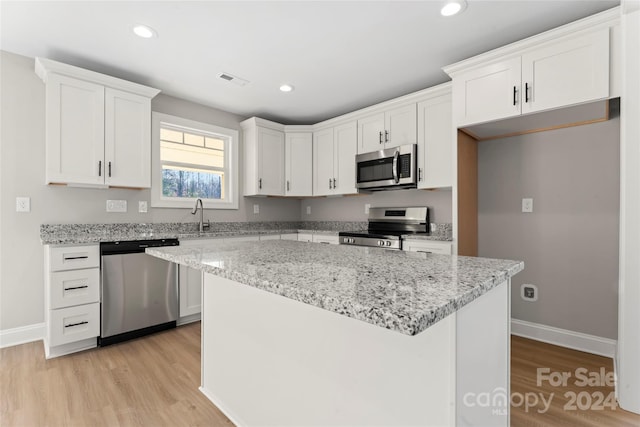 kitchen with a kitchen island, white cabinets, light wood-type flooring, and appliances with stainless steel finishes