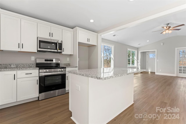 kitchen featuring hardwood / wood-style floors, white cabinets, vaulted ceiling, and appliances with stainless steel finishes