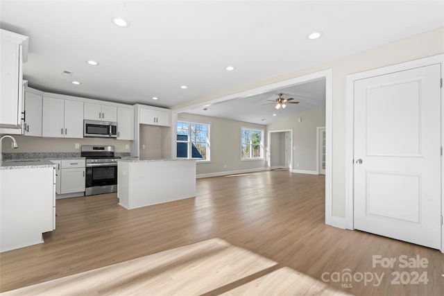 kitchen featuring white cabinets, a center island, appliances with stainless steel finishes, and light hardwood / wood-style flooring