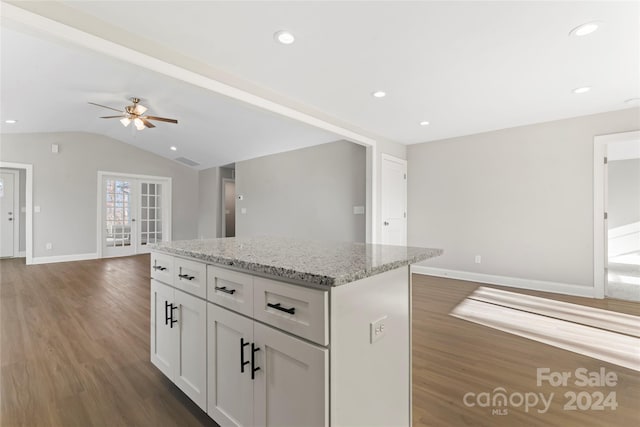 kitchen featuring light stone countertops, french doors, dark hardwood / wood-style flooring, vaulted ceiling, and white cabinets