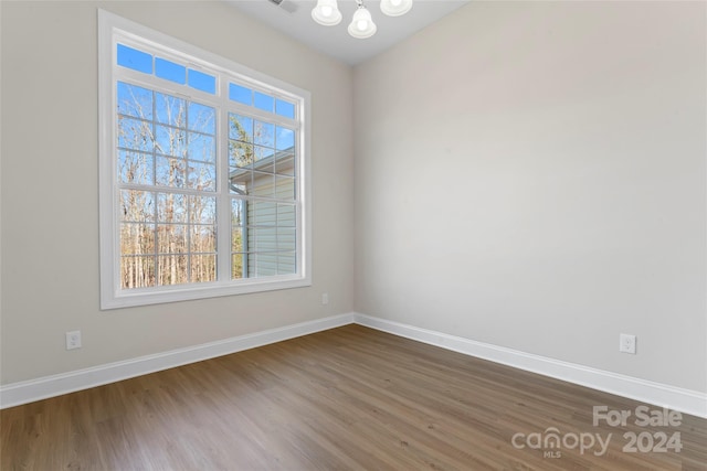 empty room featuring an inviting chandelier and hardwood / wood-style flooring