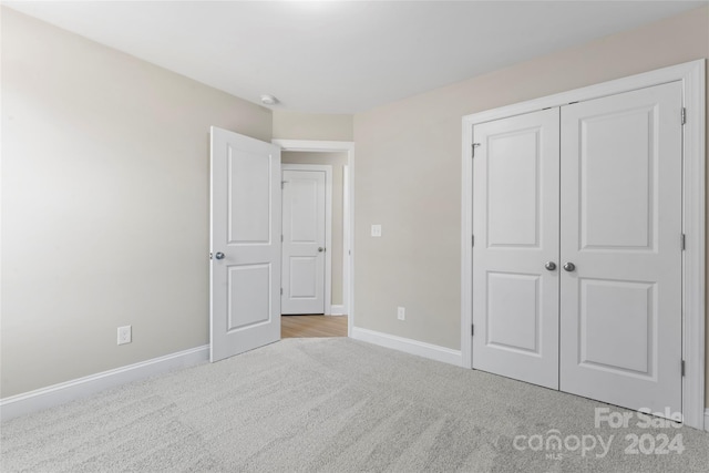 unfurnished bedroom with light carpet and a closet