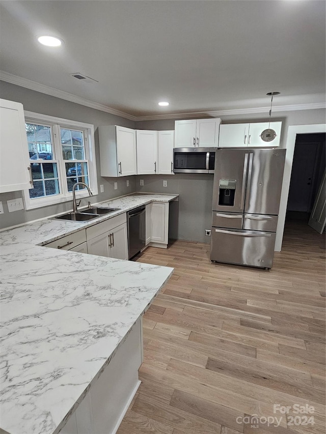 kitchen featuring white cabinetry, sink, stainless steel appliances, light hardwood / wood-style floors, and pendant lighting