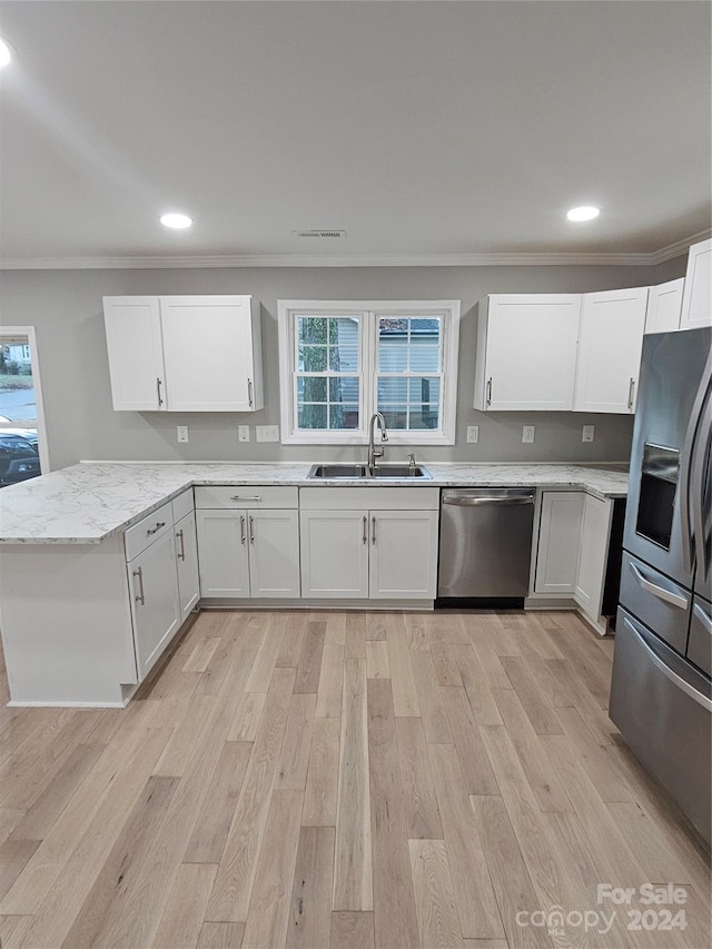 kitchen with white cabinetry, sink, light stone countertops, and appliances with stainless steel finishes