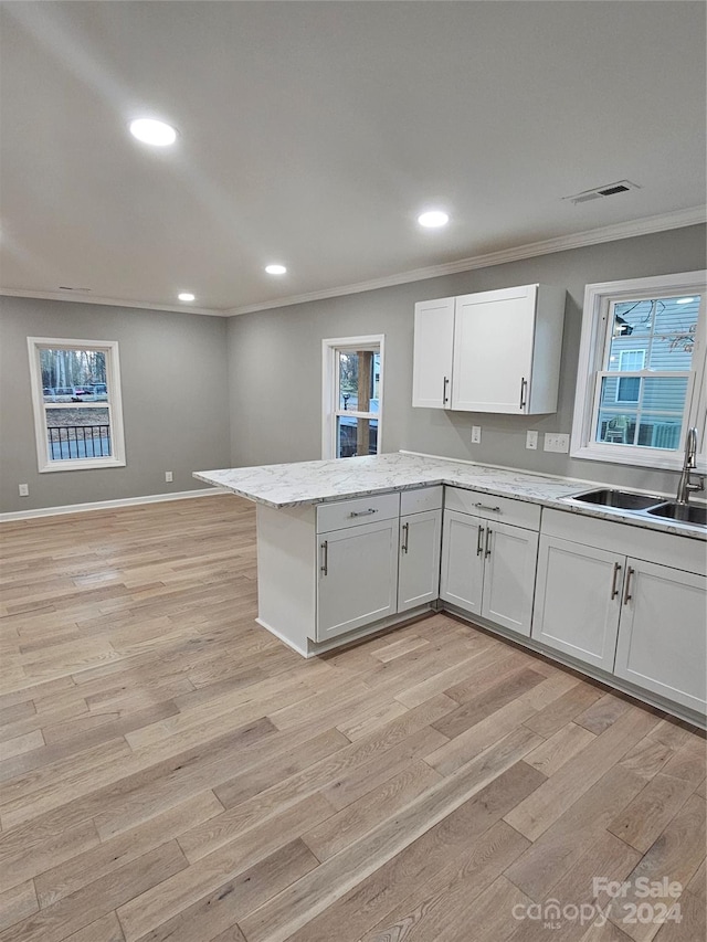 kitchen featuring white cabinets, light hardwood / wood-style floors, ornamental molding, and sink