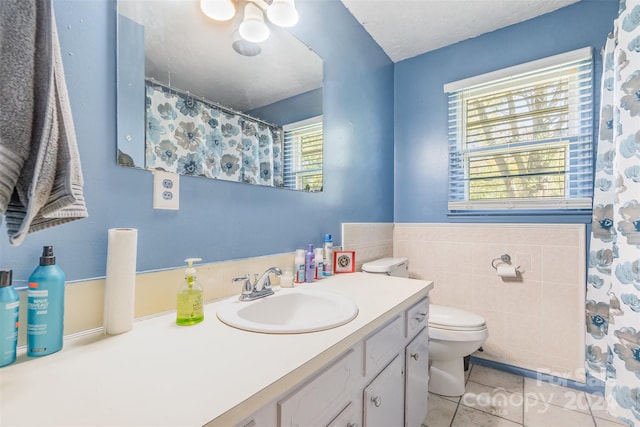 bathroom featuring tile patterned flooring, vanity, toilet, and tile walls