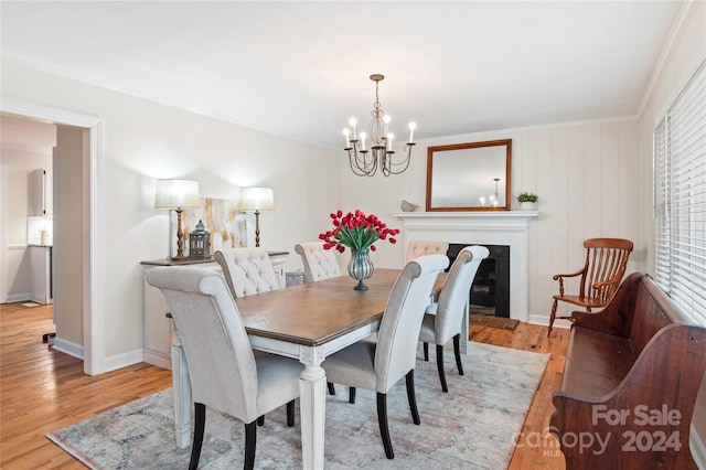 dining area with an inviting chandelier, light hardwood / wood-style floors, and ornamental molding