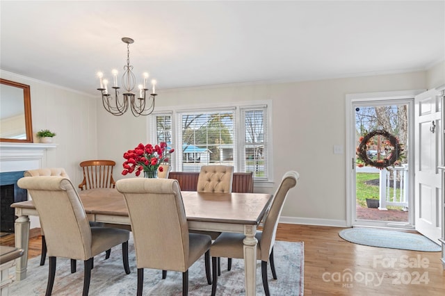 dining room featuring an inviting chandelier, light hardwood / wood-style flooring, a healthy amount of sunlight, and crown molding