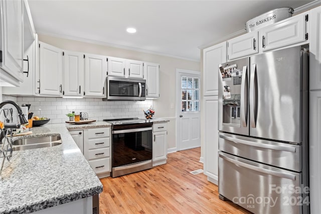 kitchen featuring white cabinets, light wood-type flooring, stainless steel appliances, and sink