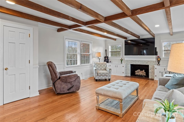 living room with beamed ceiling, light hardwood / wood-style flooring, plenty of natural light, and a fireplace