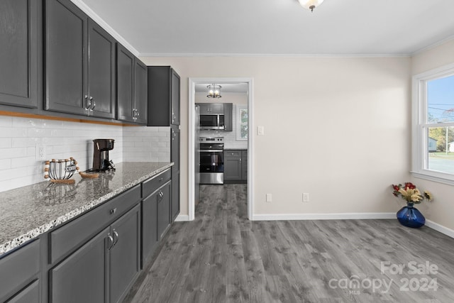 kitchen with stone counters, crown molding, stainless steel stove, tasteful backsplash, and wood-type flooring