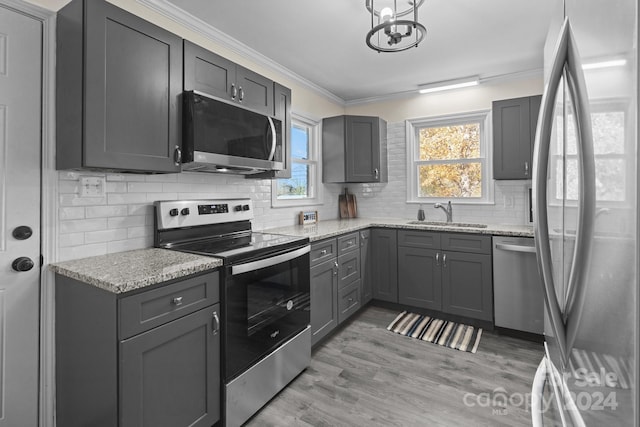 kitchen with crown molding, light hardwood / wood-style floors, sink, and stainless steel appliances