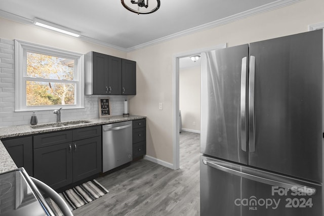 kitchen with decorative backsplash, appliances with stainless steel finishes, light wood-type flooring, light stone counters, and sink