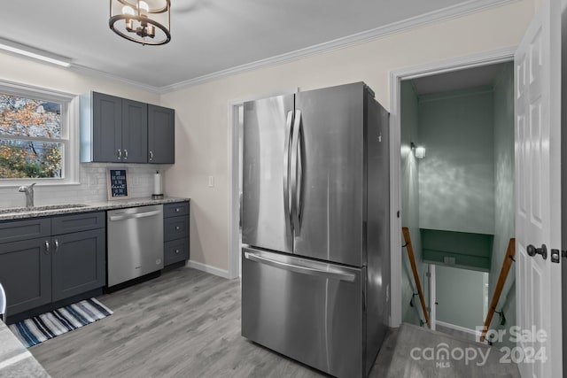 kitchen featuring crown molding, light hardwood / wood-style flooring, decorative backsplash, light stone countertops, and appliances with stainless steel finishes