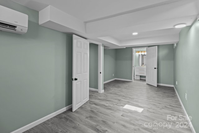 basement with a wall mounted AC and light wood-type flooring