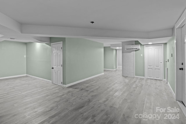 basement featuring a wall mounted AC and light hardwood / wood-style floors