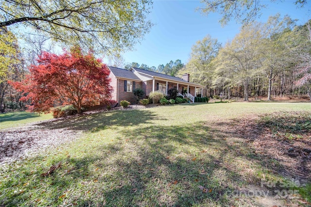 view of front of property with a porch, brick siding, a chimney, and a front lawn