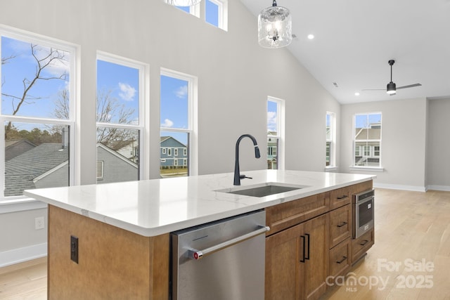 kitchen featuring sink, decorative light fixtures, high vaulted ceiling, a center island with sink, and dishwasher