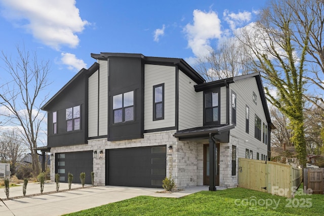 view of front of house with an attached garage, fence, stone siding, concrete driveway, and a front yard