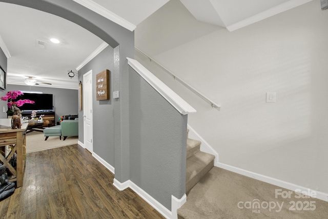 stairs featuring visible vents, wood finished floors, arched walkways, crown molding, and baseboards