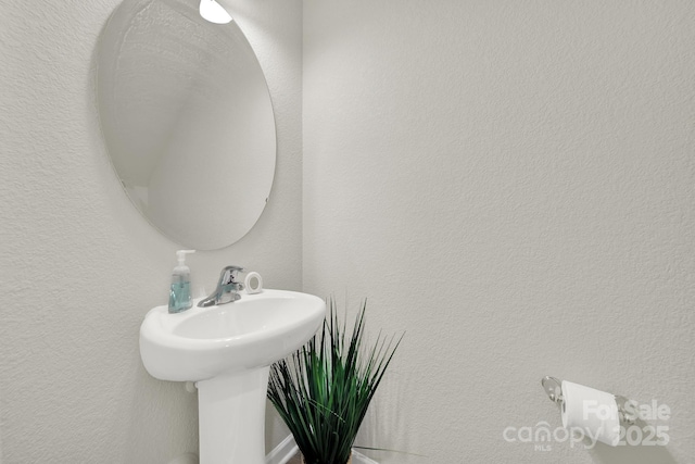 bathroom with a textured wall and a sink