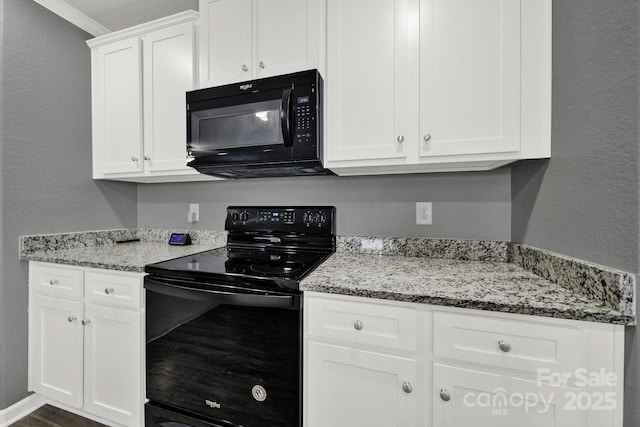 kitchen featuring light stone counters, black appliances, white cabinets, and a textured wall