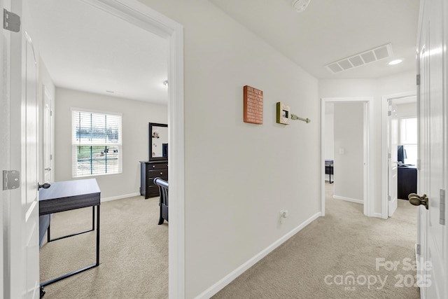 hallway with carpet, visible vents, and baseboards