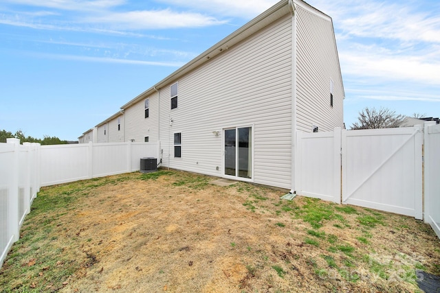 rear view of house with a yard, a fenced backyard, and a gate