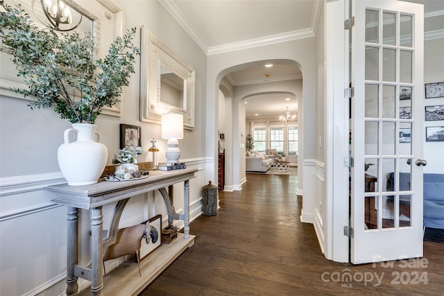 hall with ornamental molding, french doors, dark wood-type flooring, and a notable chandelier