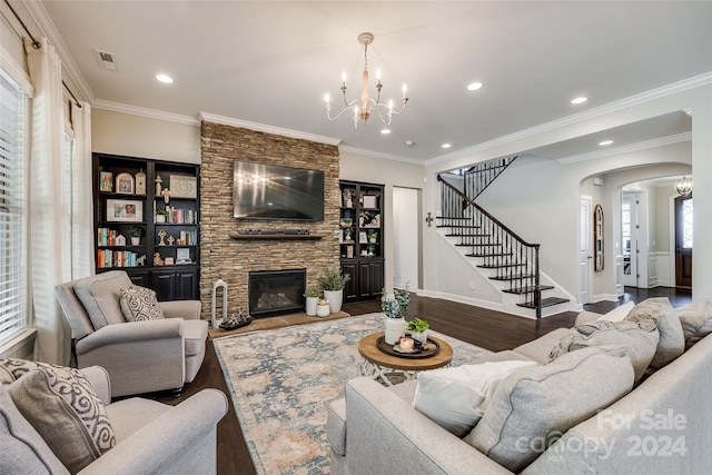 living room featuring a fireplace, crown molding, dark wood-type flooring, and an inviting chandelier