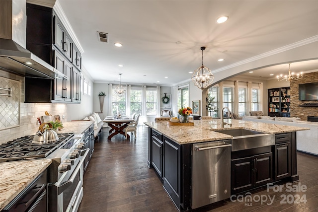 kitchen with sink, hanging light fixtures, dark wood-type flooring, stainless steel appliances, and a center island with sink