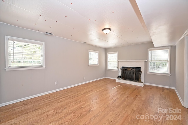 unfurnished living room with light hardwood / wood-style floors and a brick fireplace