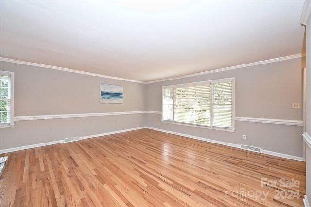 spare room featuring plenty of natural light, light hardwood / wood-style floors, and ornamental molding