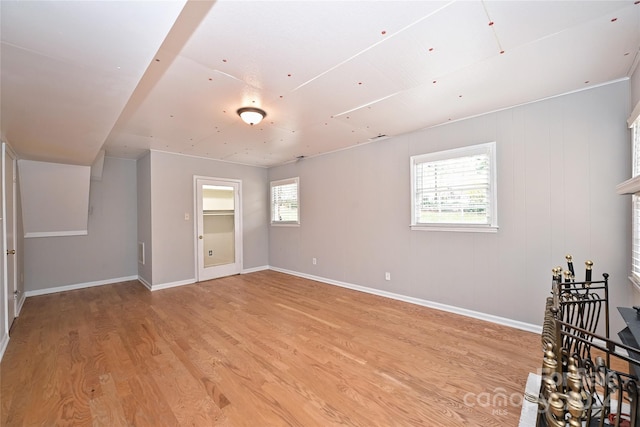 unfurnished room with plenty of natural light, wood walls, and light hardwood / wood-style flooring