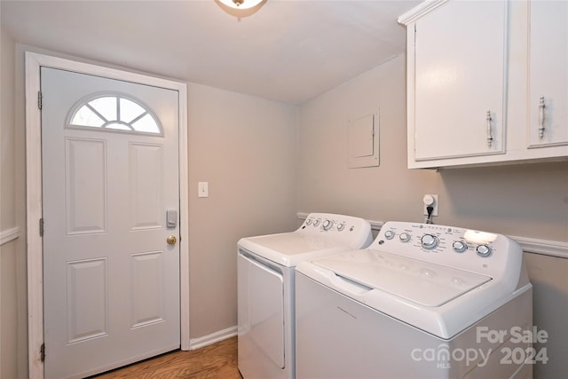 clothes washing area with washer and clothes dryer, light hardwood / wood-style floors, and cabinets