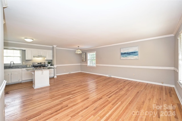 unfurnished living room featuring light wood-type flooring, ornamental molding, and sink