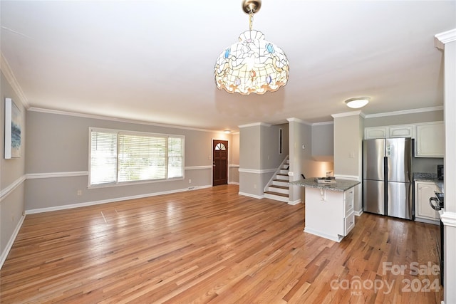 kitchen with stainless steel fridge, light hardwood / wood-style floors, white cabinetry, and hanging light fixtures