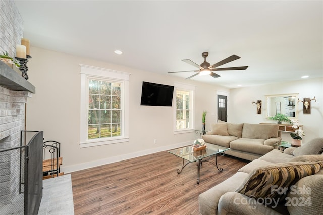 living room with ceiling fan, a fireplace, and wood-type flooring