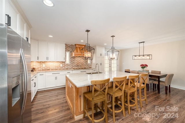 kitchen featuring stainless steel refrigerator with ice dispenser, dark hardwood / wood-style flooring, sink, a center island with sink, and white cabinetry