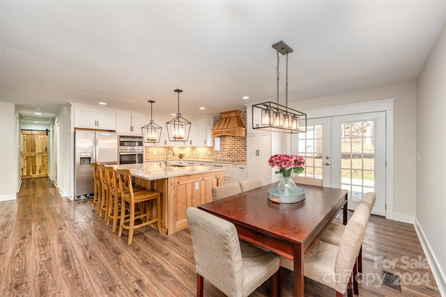 dining area with sink, french doors, and hardwood / wood-style flooring