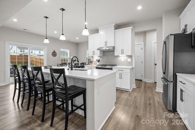 kitchen featuring stainless steel appliances, white cabinetry, sink, and pendant lighting