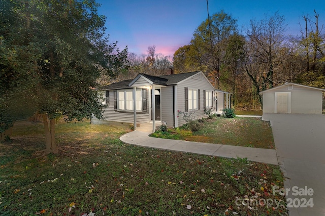 property exterior at dusk featuring a yard and a storage shed