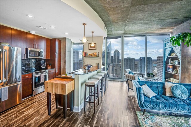 kitchen with pendant lighting, a kitchen bar, dark stone counters, dark hardwood / wood-style flooring, and stainless steel appliances