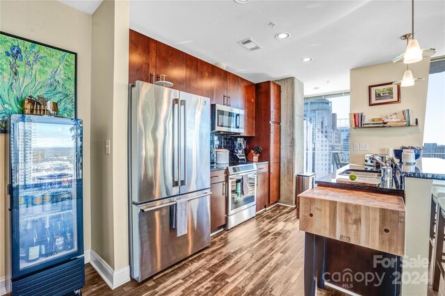 kitchen with hardwood / wood-style floors, wood counters, sink, decorative light fixtures, and stainless steel appliances