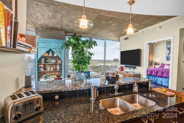 kitchen featuring sink, ceiling fan, dark stone countertops, and hanging light fixtures