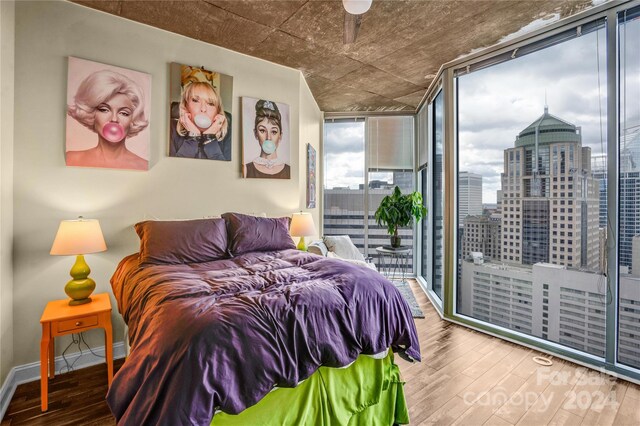 bedroom with access to outside, expansive windows, and wood-type flooring