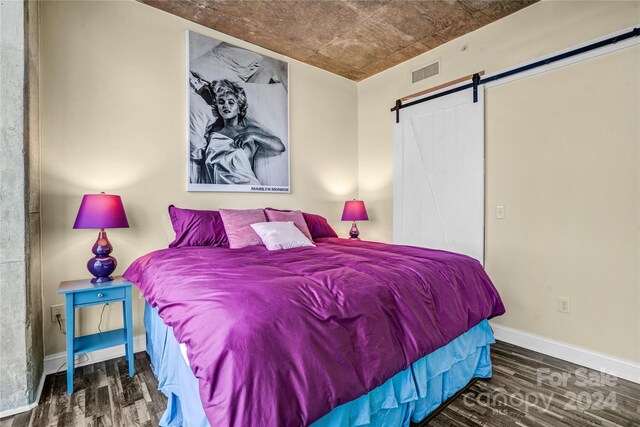 bedroom featuring a barn door and dark hardwood / wood-style floors