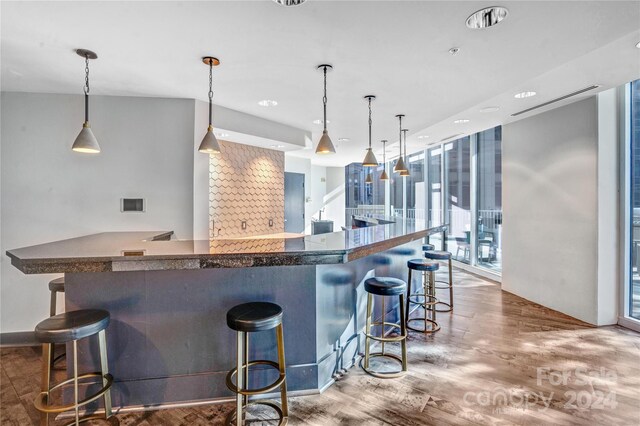 kitchen featuring floor to ceiling windows, a breakfast bar, decorative light fixtures, and hardwood / wood-style flooring