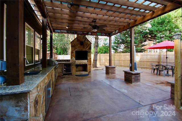 view of patio featuring an outdoor kitchen, a pergola, an outdoor stone fireplace, ceiling fan, and grilling area